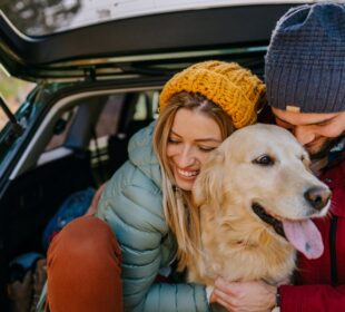 A couple holding the dog and sitting in car