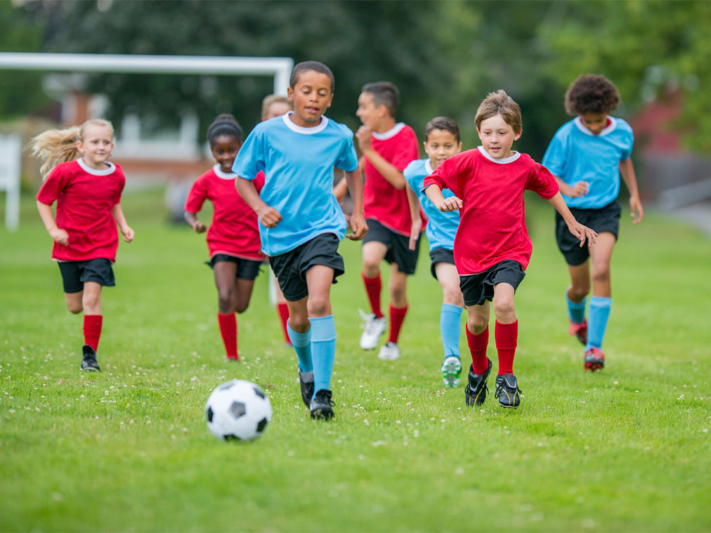 A group of kids playing football game in ground